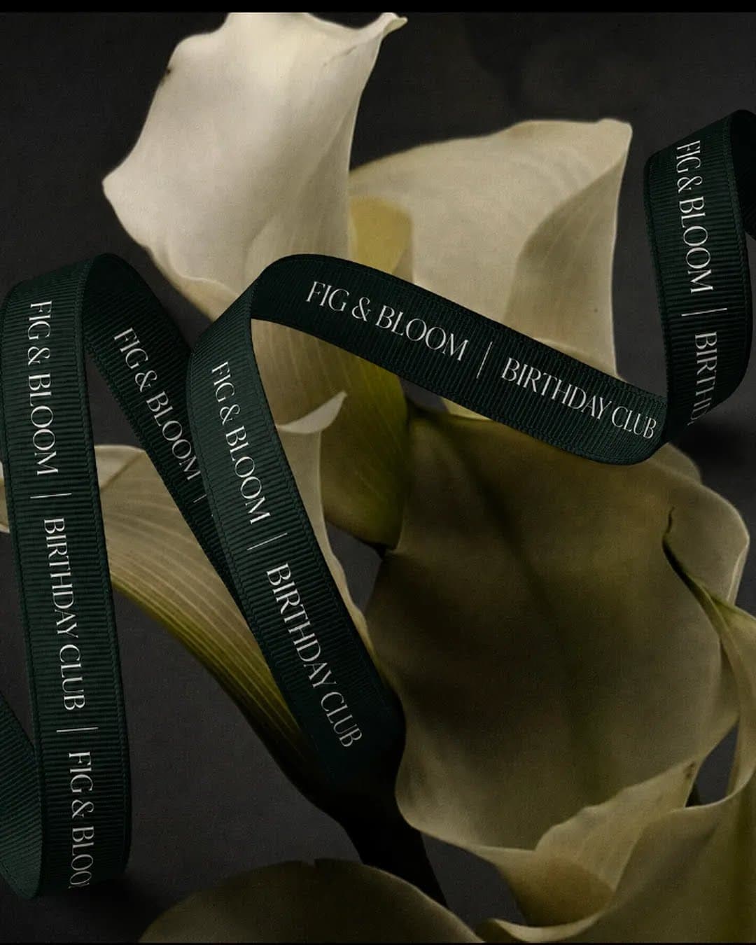 Ivory calla lilies wrapped in evergreen Fig & Bloom Birthday Club ribbon